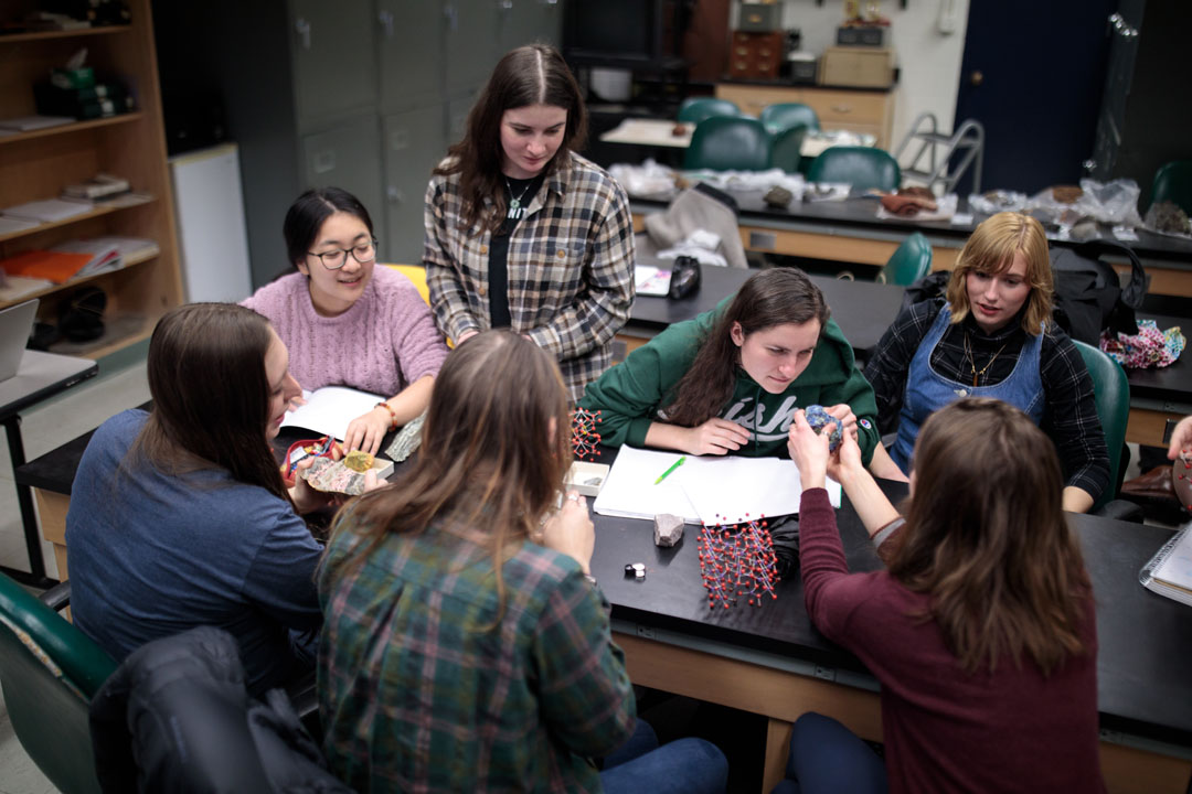 students work with rock samples and molecular models at a classroom table