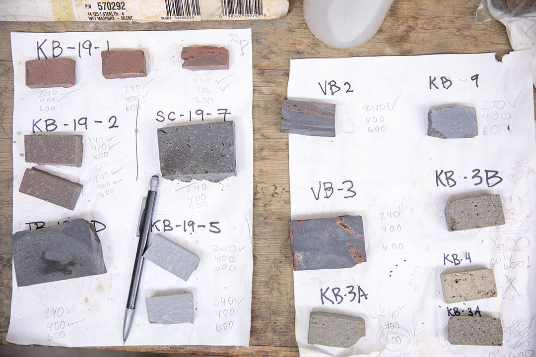 Rows of volcanic rock samples labeled and laid out on white papers