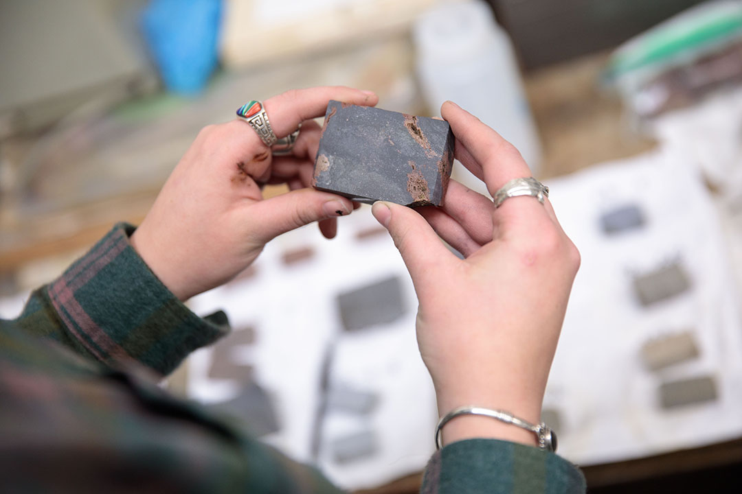 A rectangular rock sample held in two hands