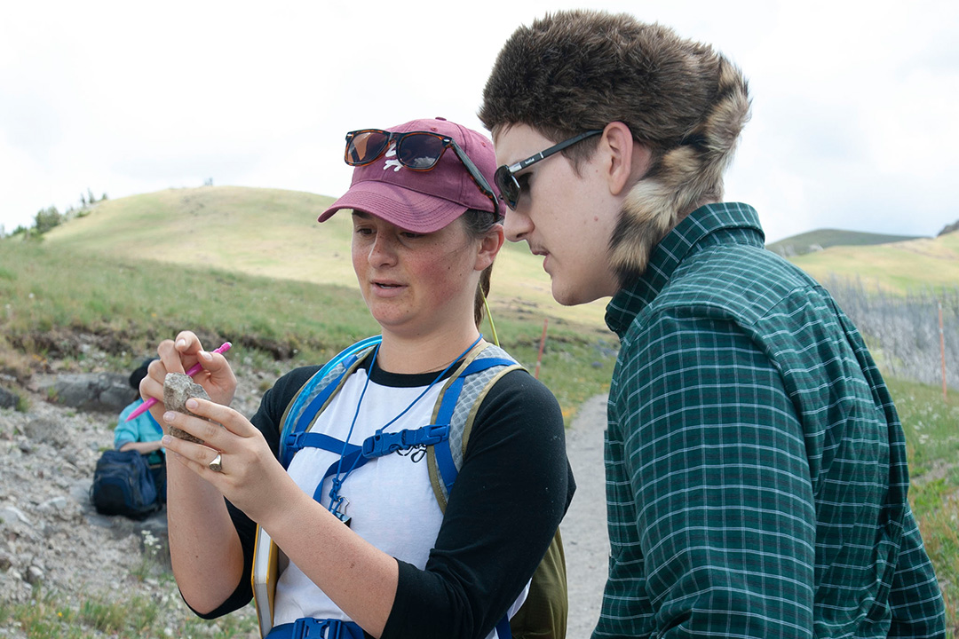 2 geology students examine a rock sample on the field